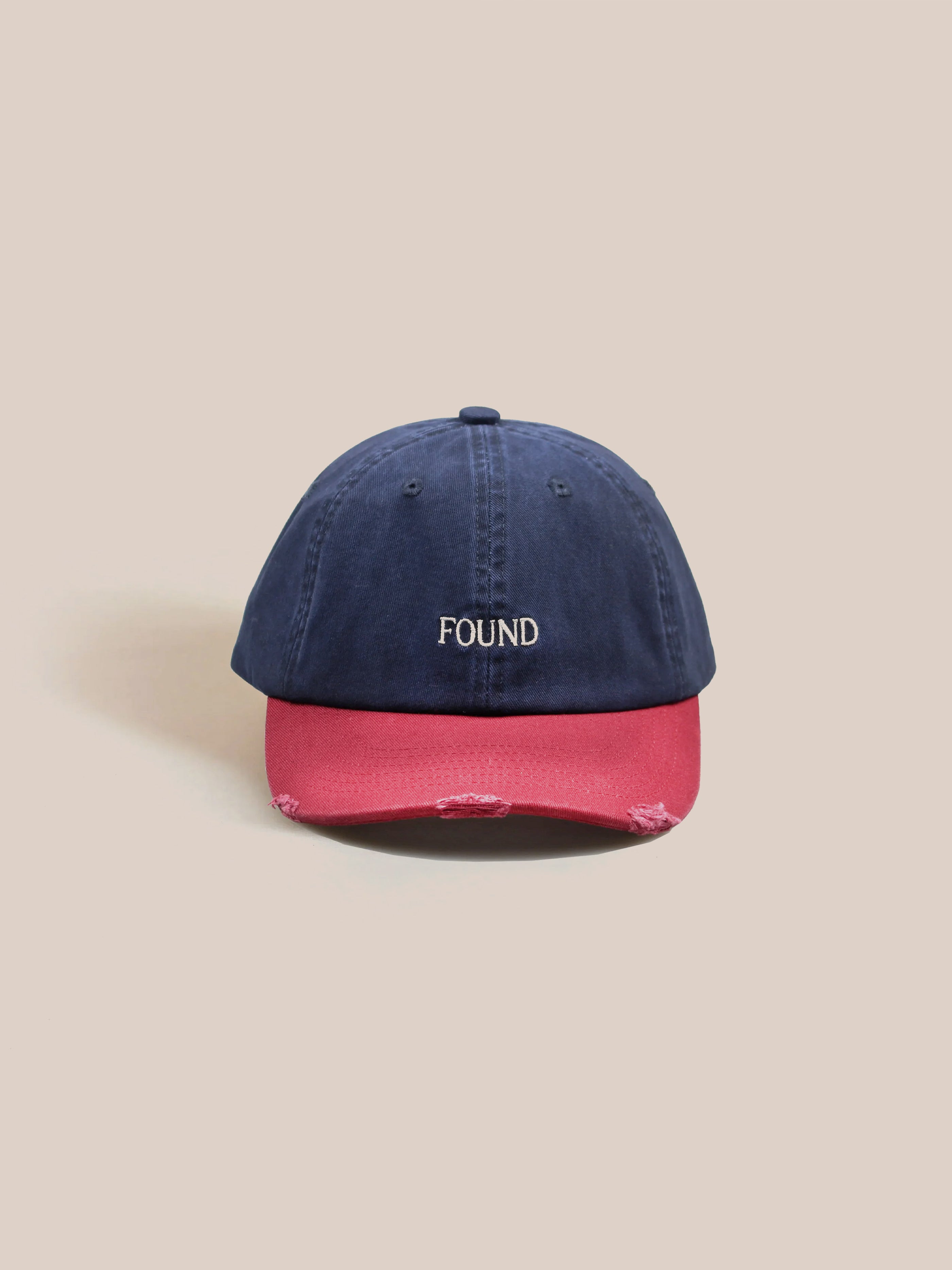 This FOUND Two-Tone Logo Cap showcases a midnight navy top paired with a burnt clay brim, featuring the brand name embroidered prominently on the front.