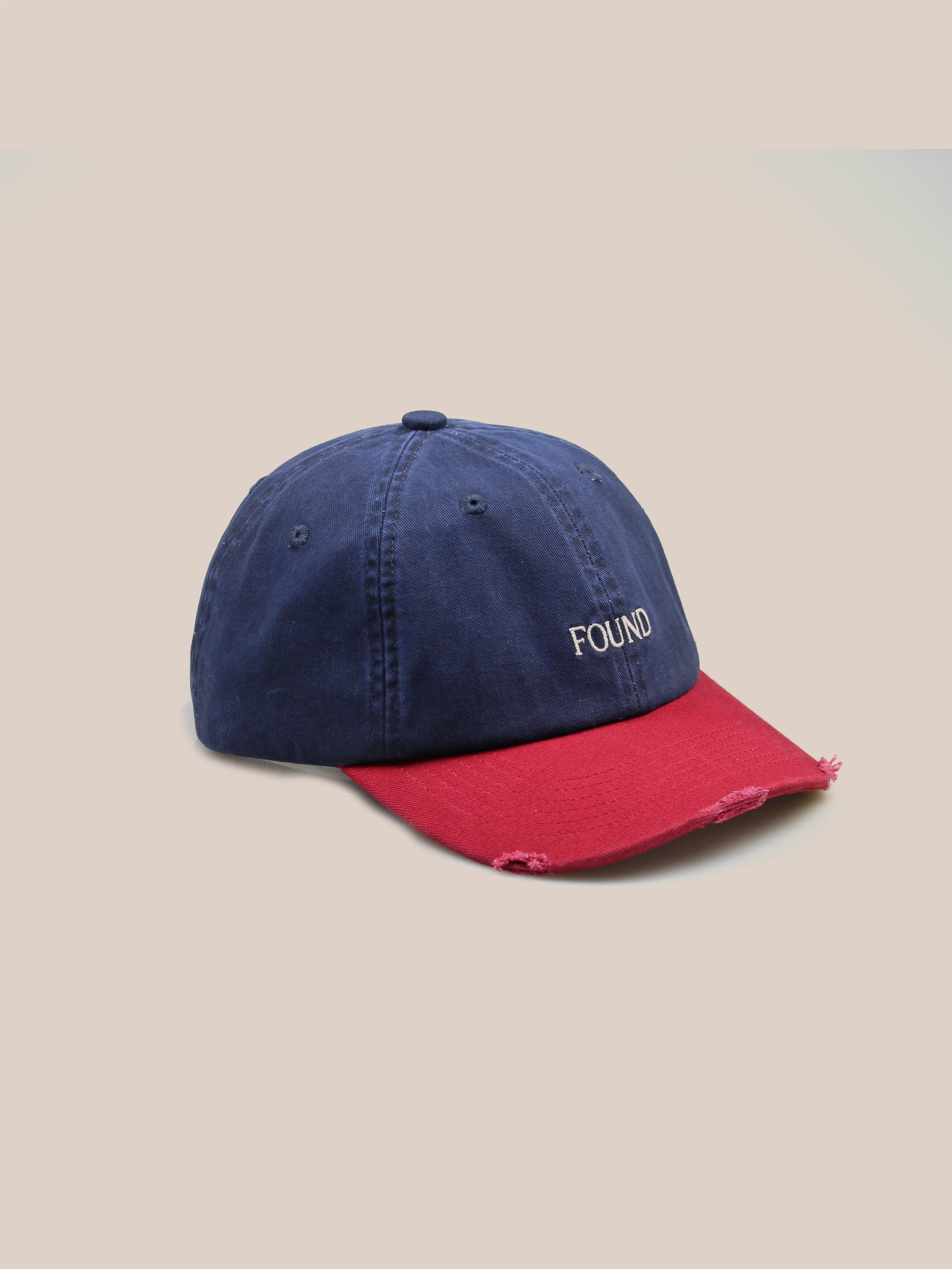 A Two-Tone Logo Cap by FOUND, featuring a classic 6-panel shape and elegant "FOUND" embroidery on the front in blue and red.