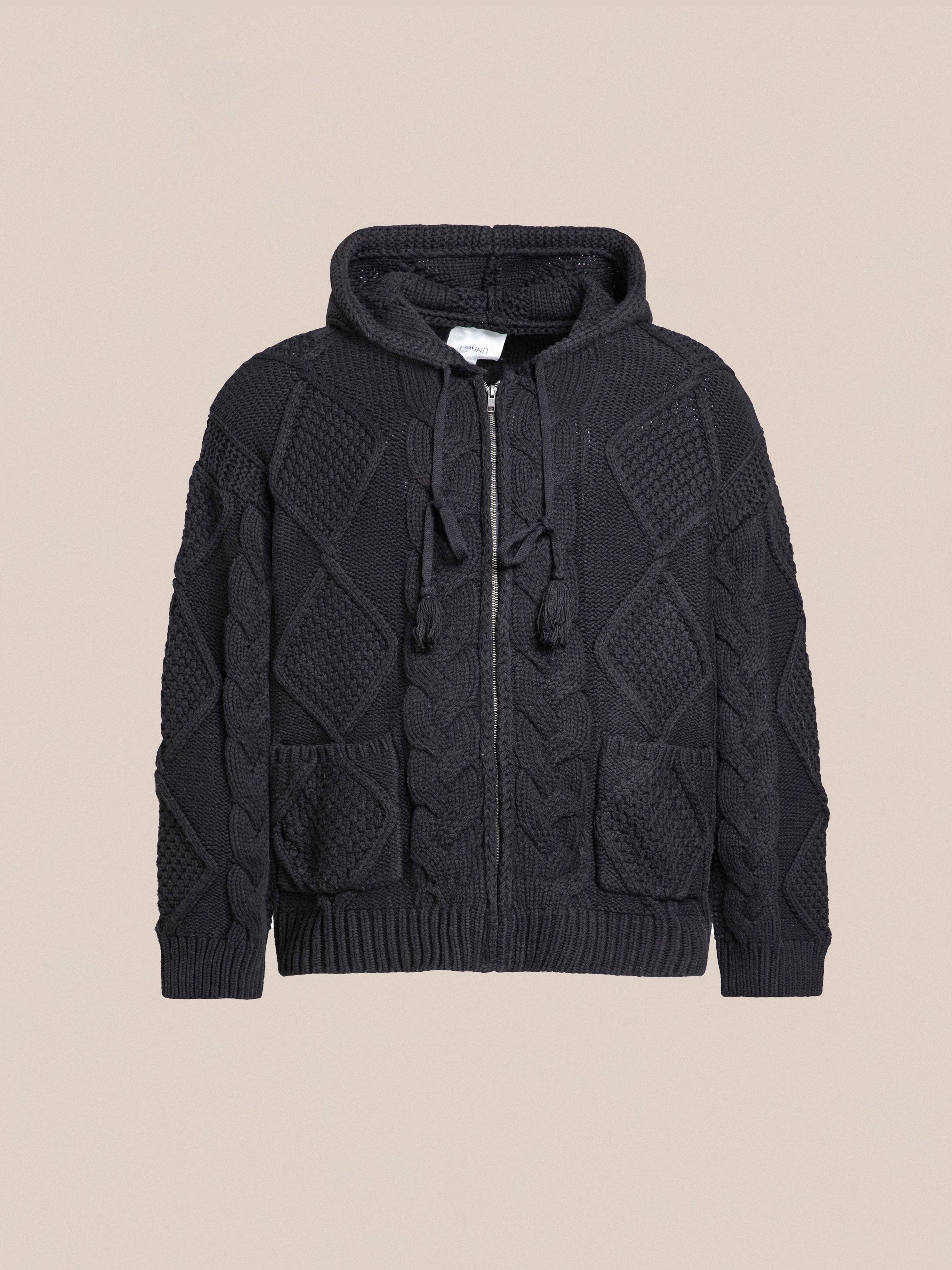 The black Zip Up Cable Knit Hoodie by Found features a front zipper, crafted from a heavyweight cotton blend for durability and comfort. Its unisex relaxed fit enhances its versatile style, and it's shown against a plain background.