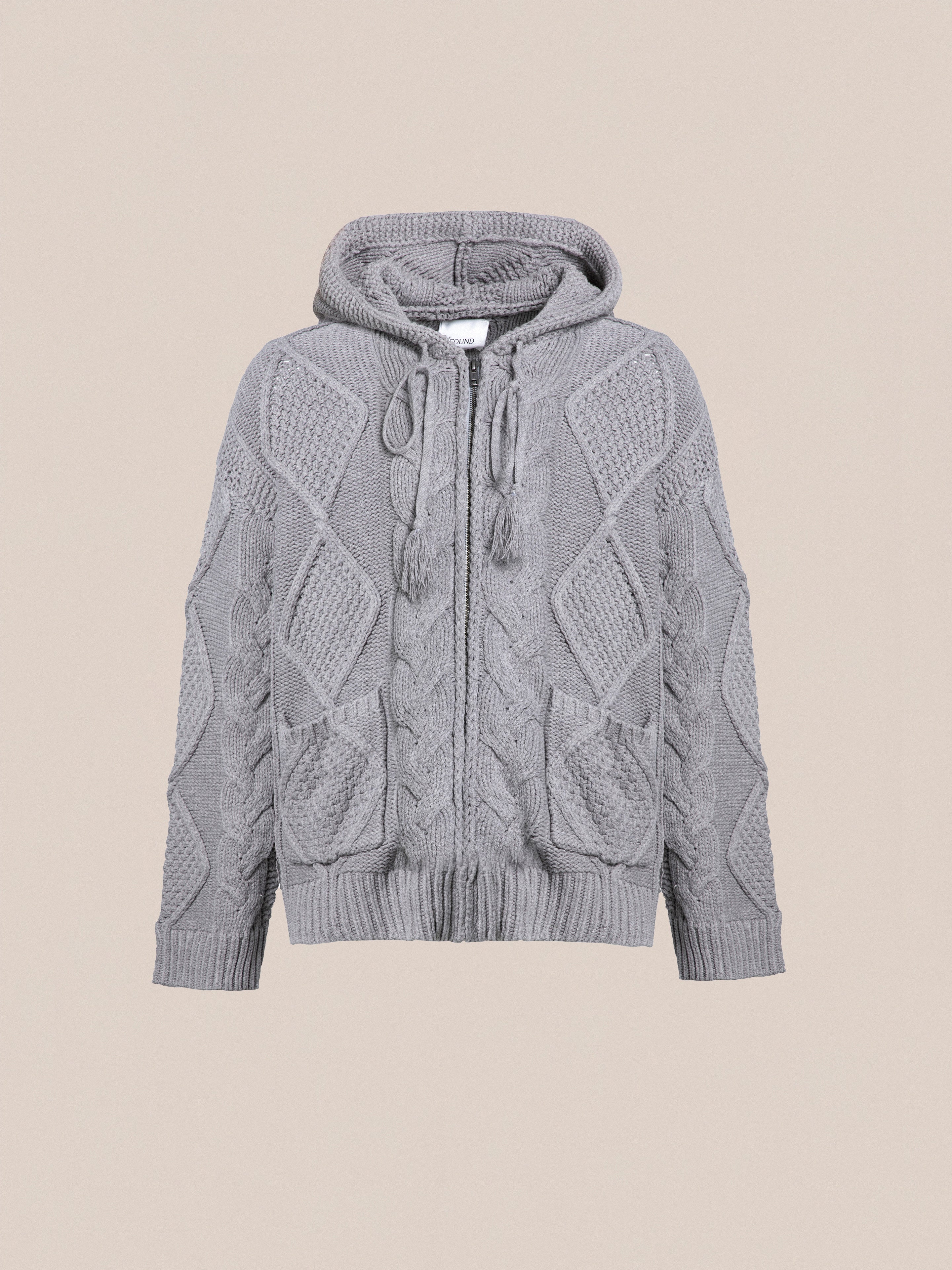 A gray Found Zip Up Cable Knit Hoodie featuring intricate cable patterns and drawstrings, designed with two front pockets, offering chunky knit comfort and warmth.